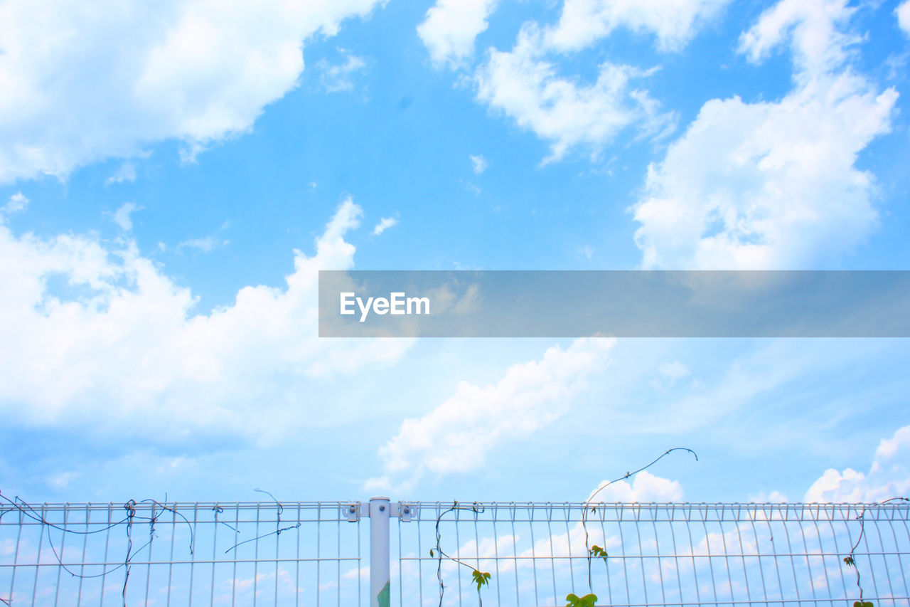 Low angle view of barbed wire fence against sky