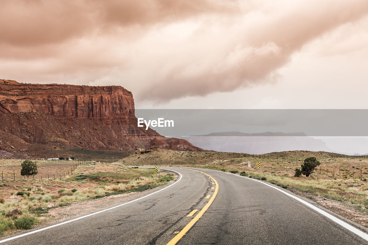 ROAD LEADING TOWARDS ROCK FORMATION AGAINST SKY