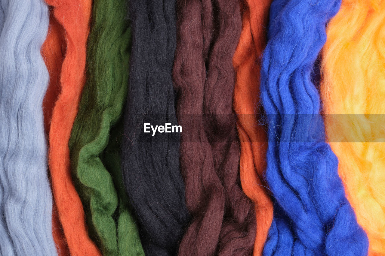 Wool of different colors and textures. background made of wool felting in form of lines. top view