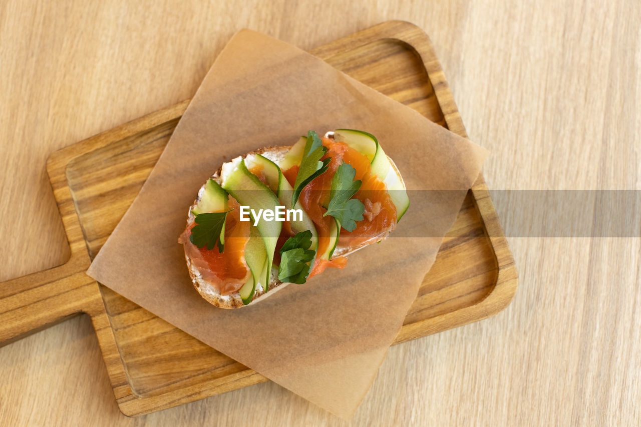 Appetizing bruschetta sandwich made from whole grain bread, with red fish and curd cheese, cucumber.