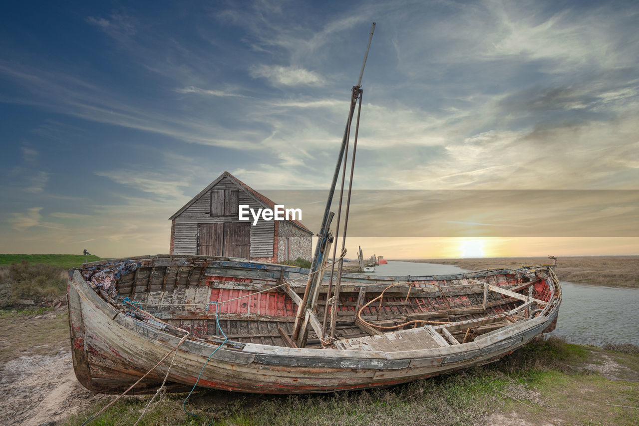 FISHING BOAT ON SHORE AGAINST SKY DURING SUNSET