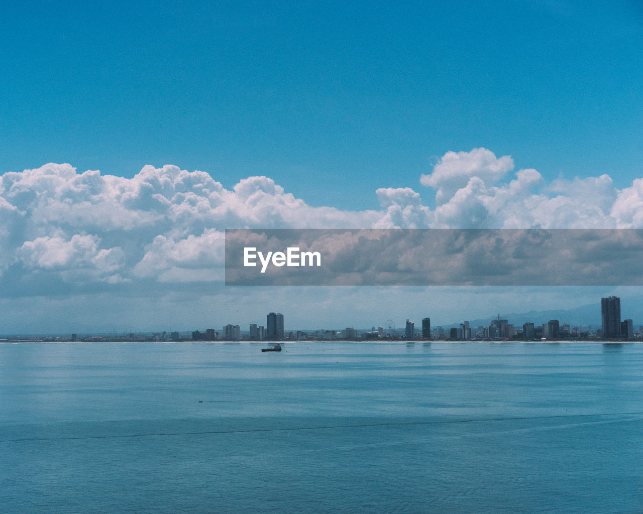 SCENIC VIEW OF SEA BY BUILDINGS AGAINST BLUE SKY