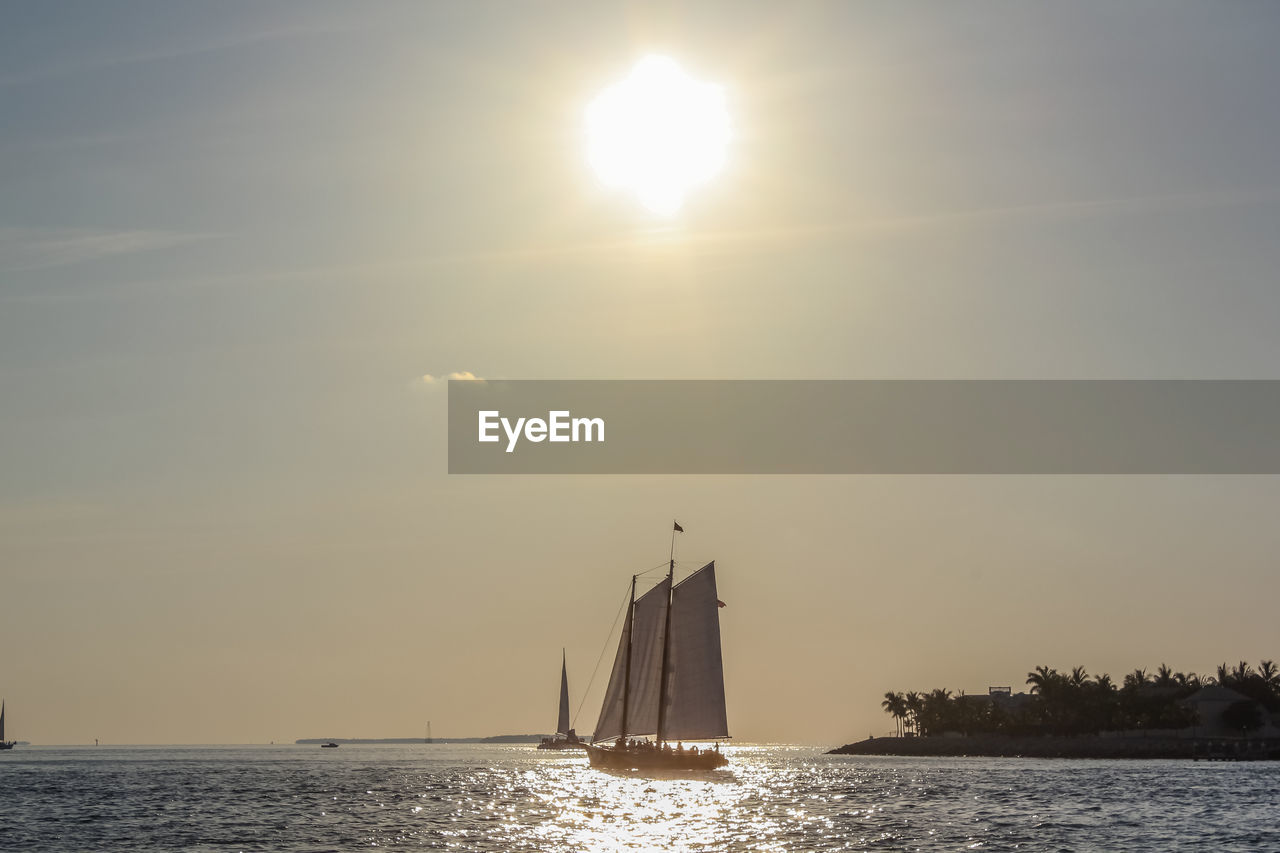 Sailboat sailing on sea against sky during sunset