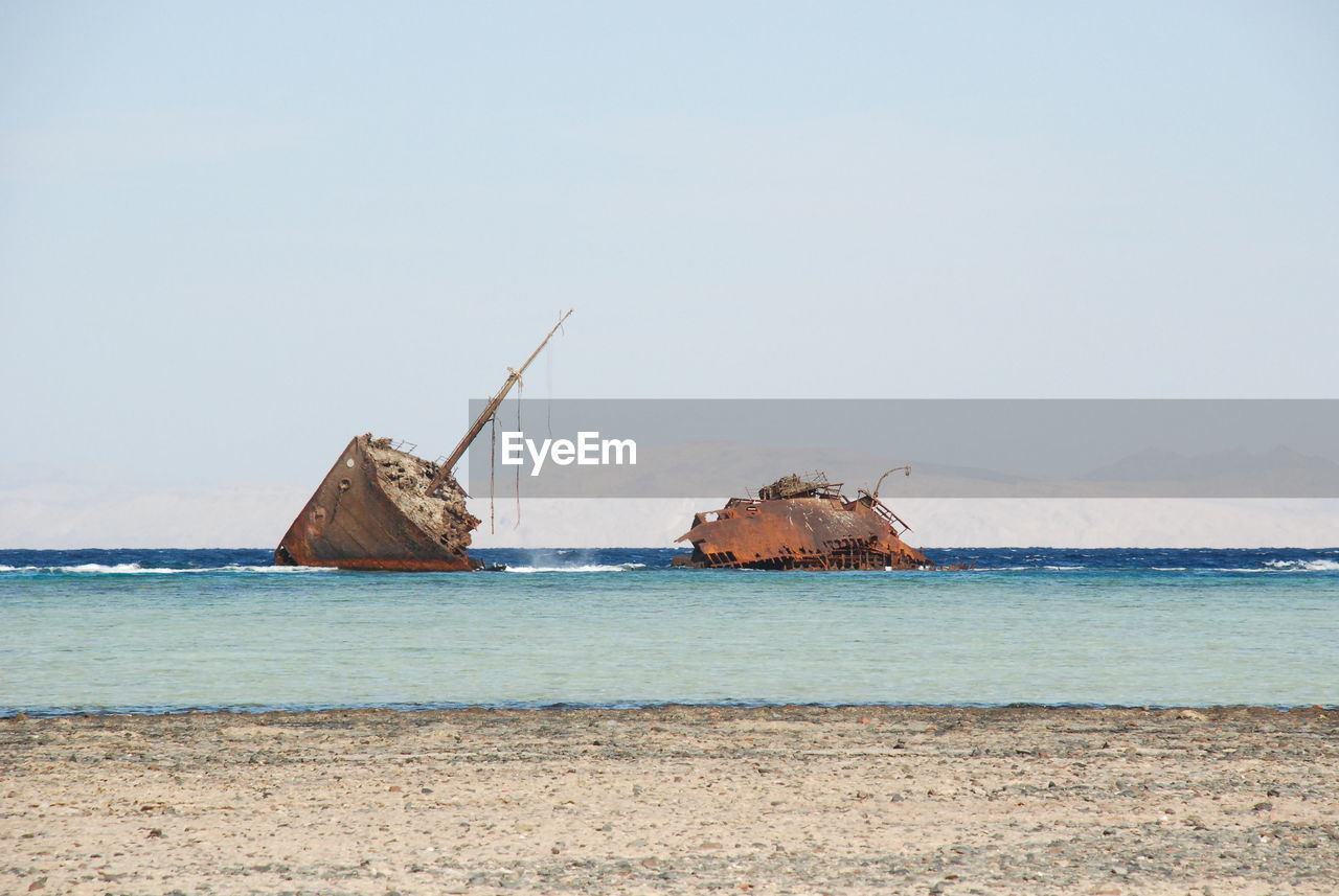 Damaged ship on beach against sky