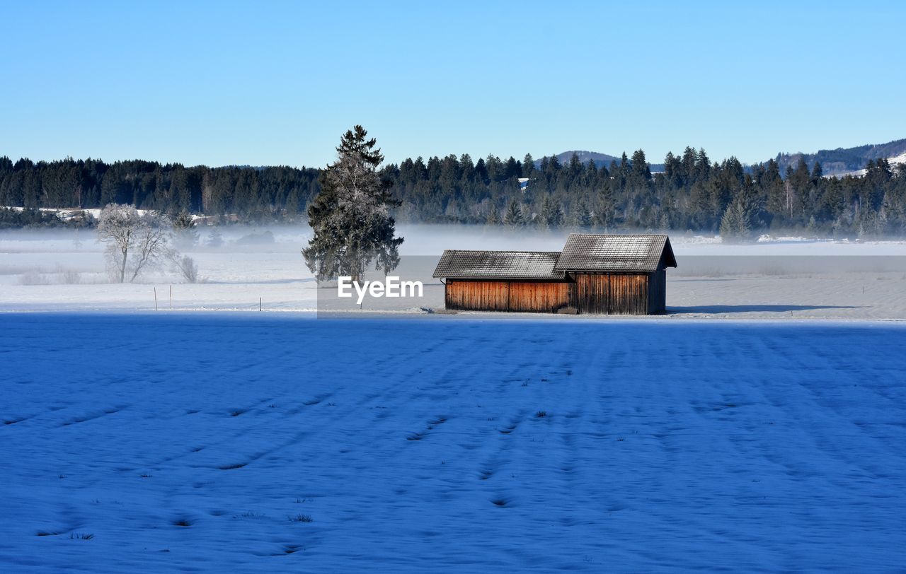 BUILT STRUCTURE ON FROZEN LAKE AGAINST CLEAR SKY