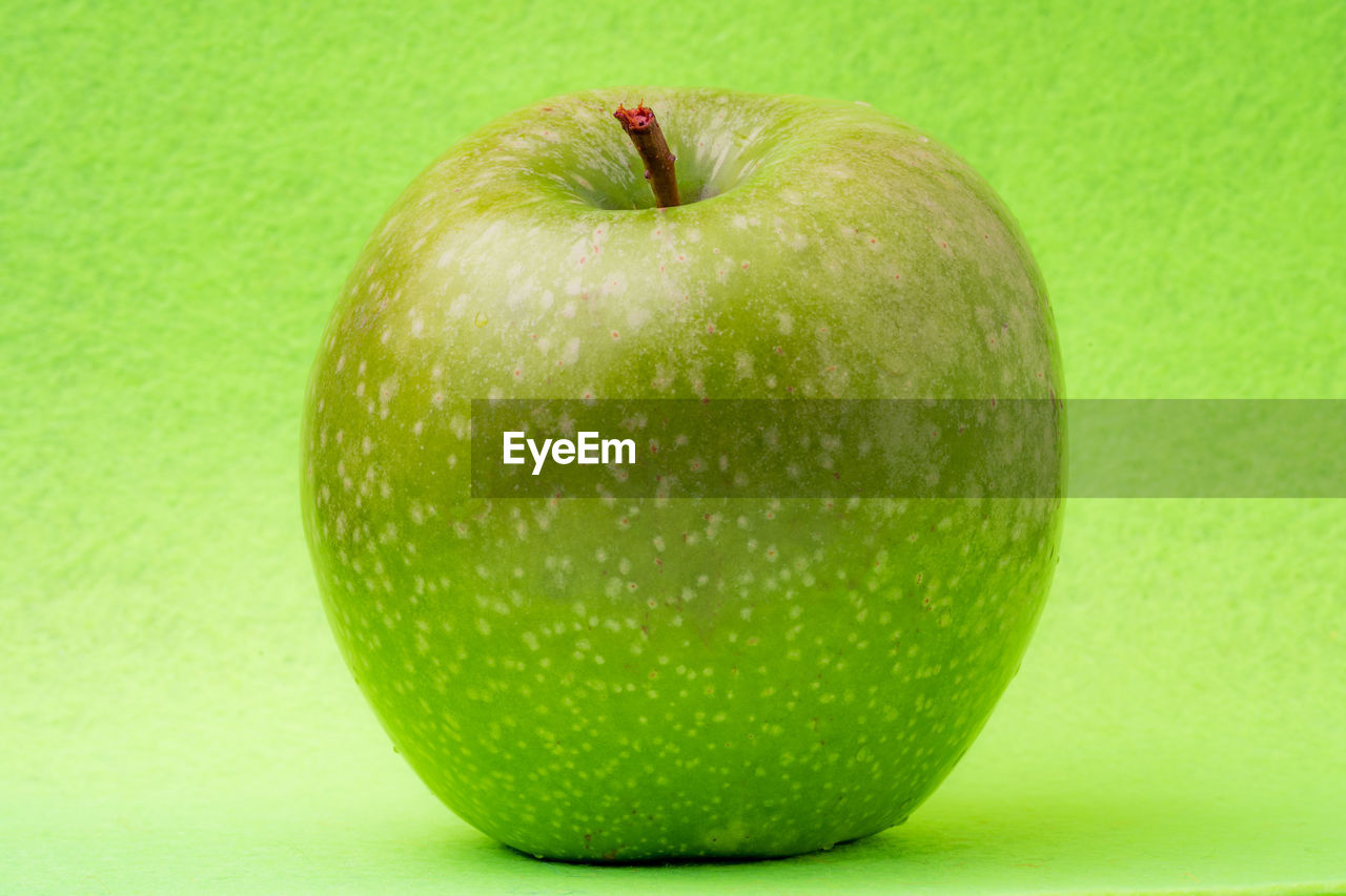 CLOSE-UP OF APPLE ON GREEN LEMON