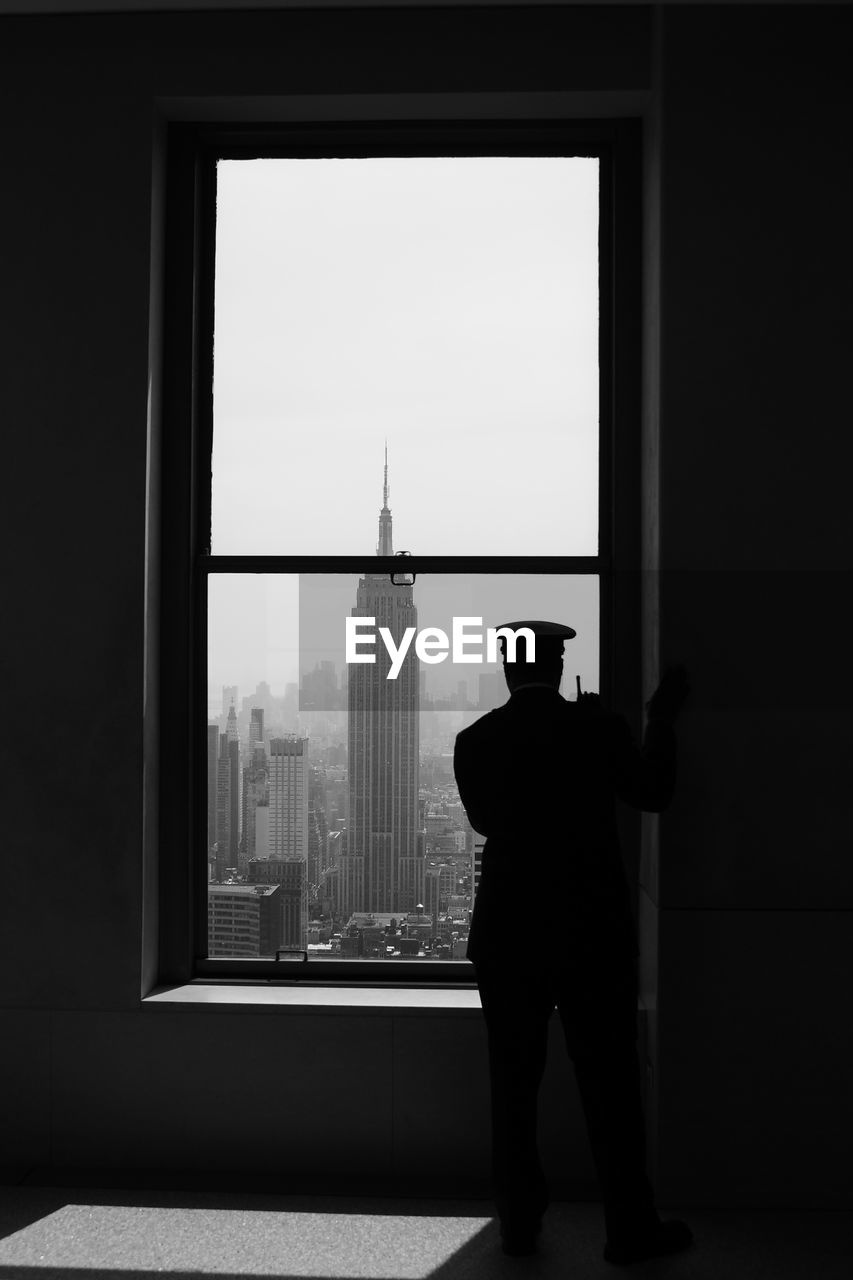 Rear view of policeman looking through window