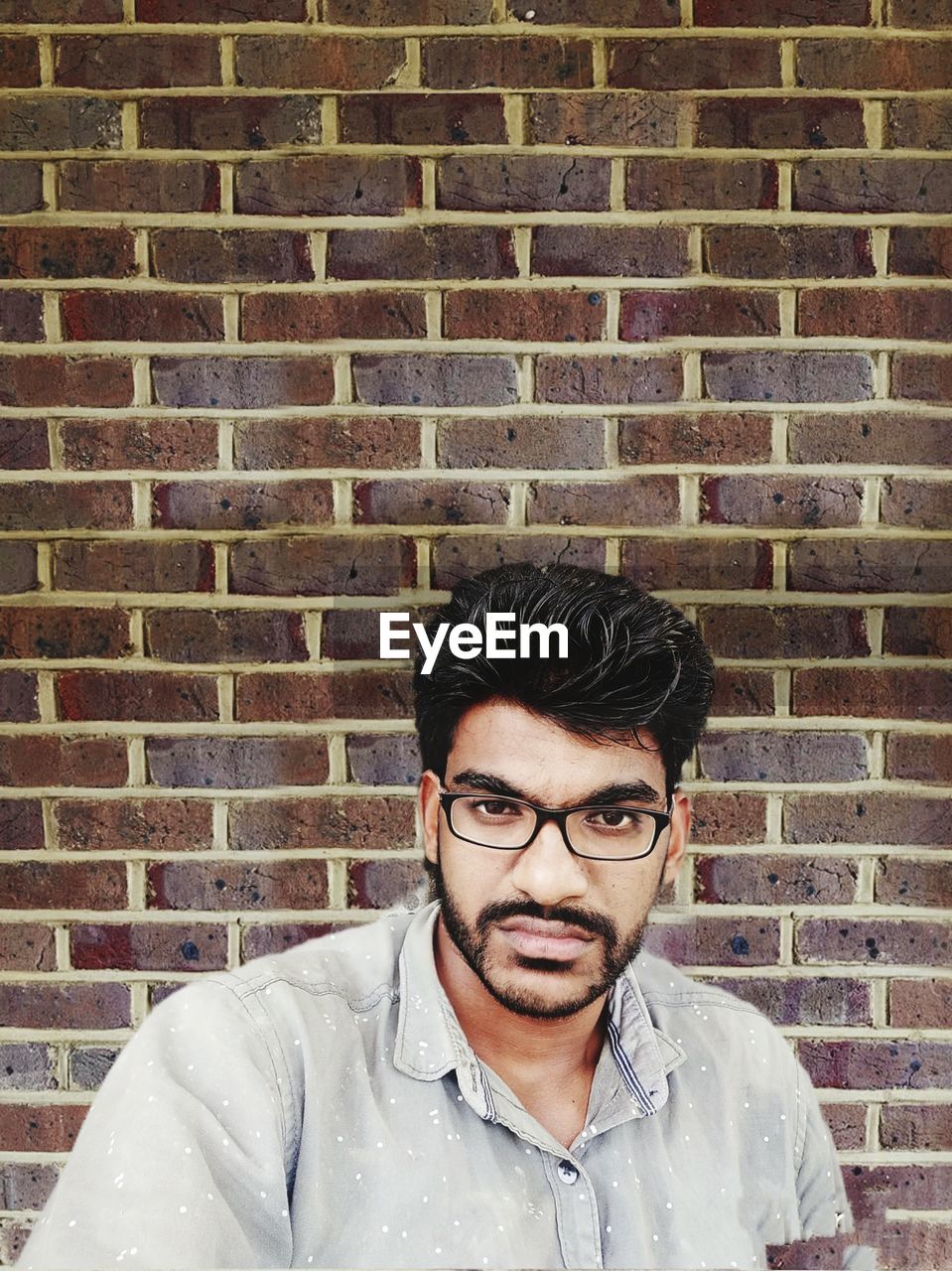 PORTRAIT OF MAN AGAINST BRICK WALL