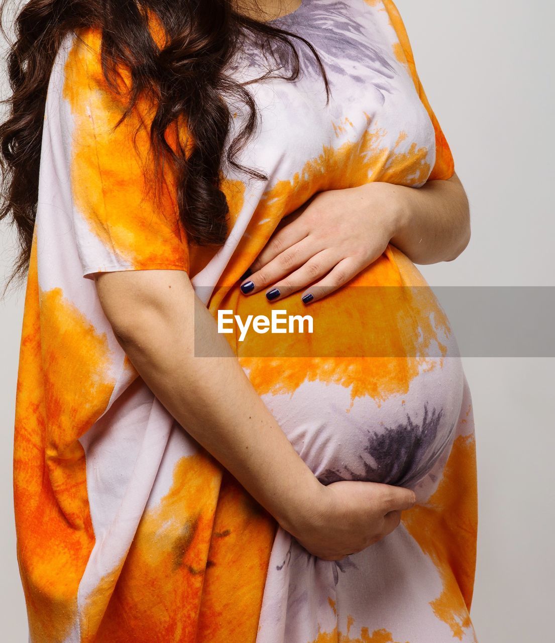 Midsection of pregnant woman holding abdomen against white background