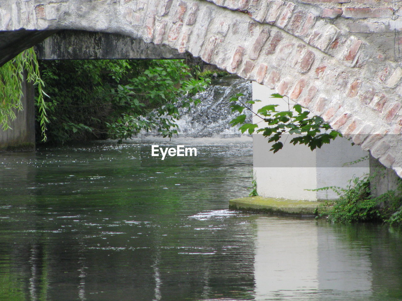 ARCH BRIDGE OVER RIVER AGAINST TREES