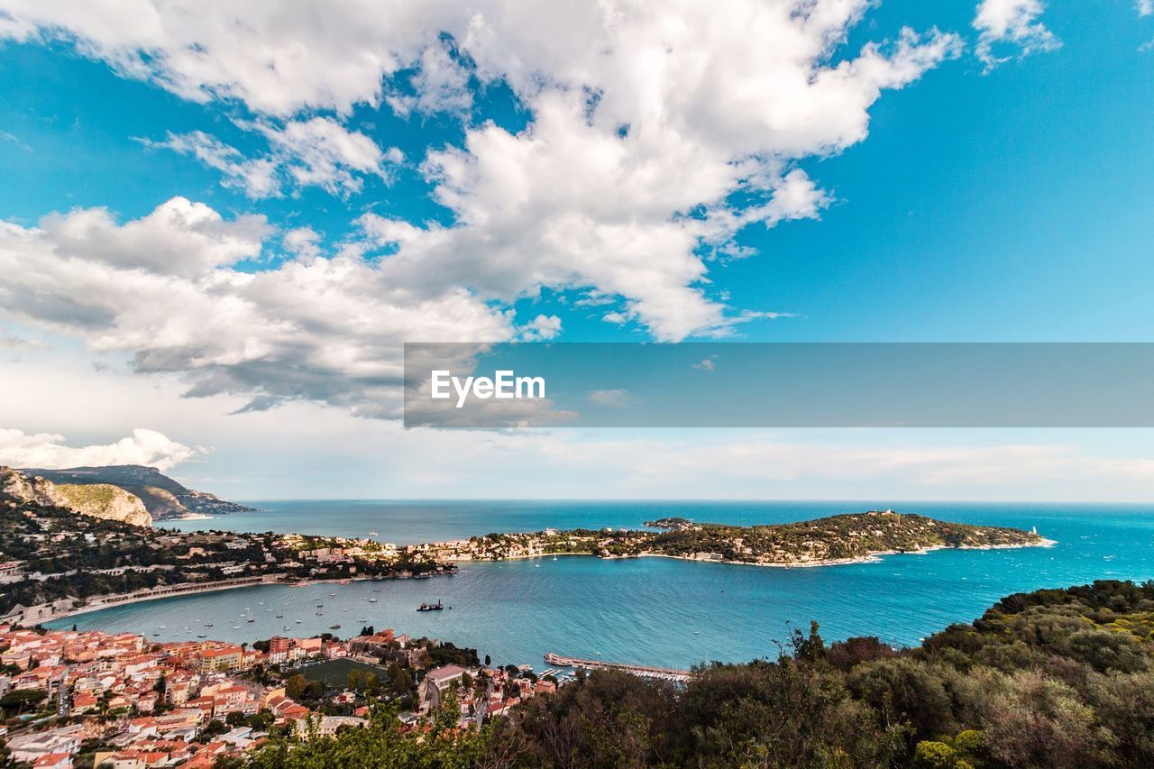 Panoramic view of city by sea against blue sky