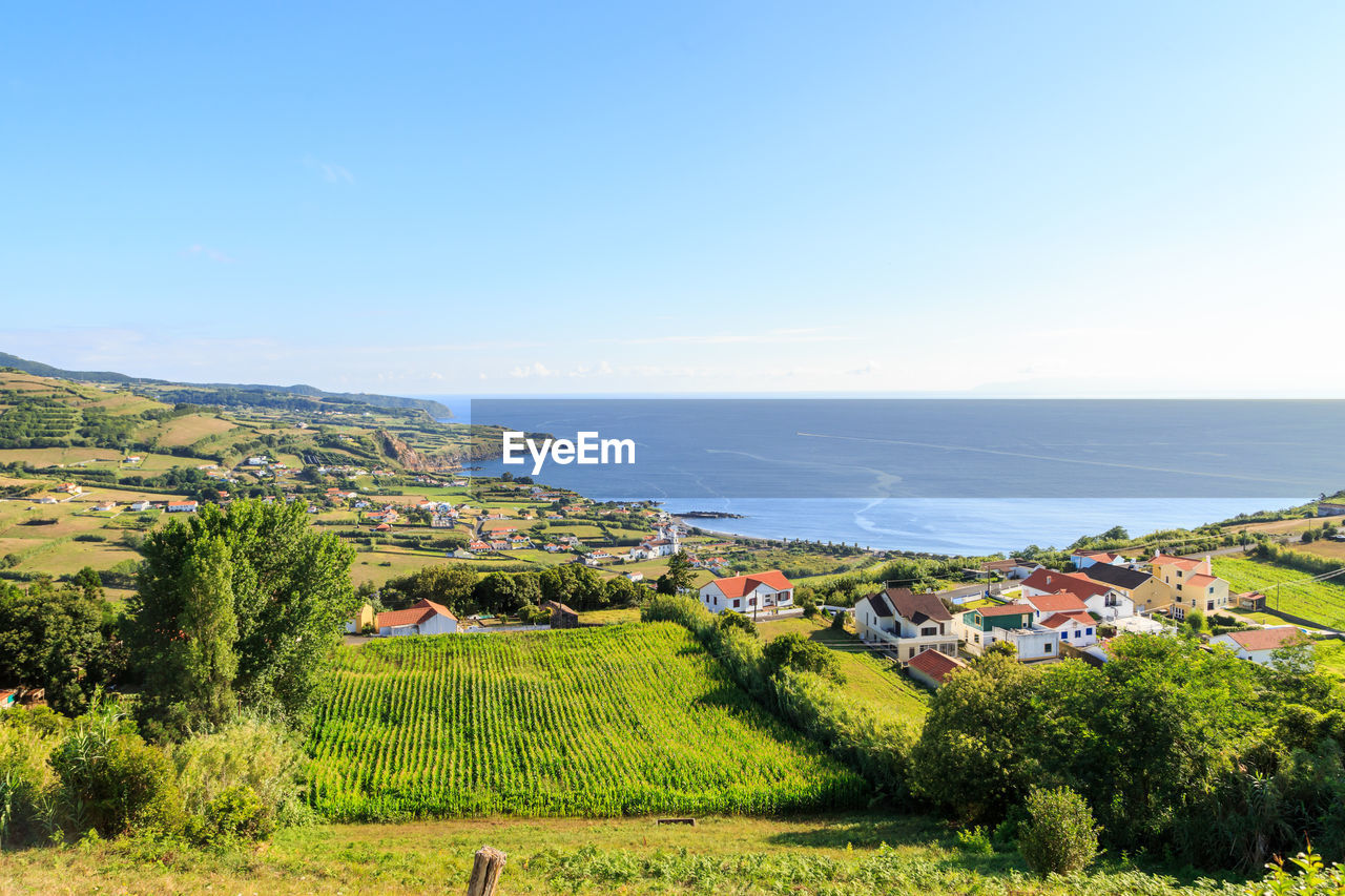 Scenic view of agricultural field by sea against sky