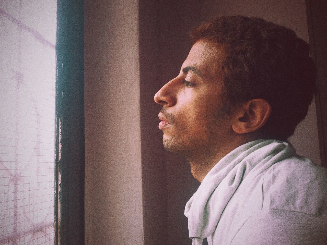 Side view of thoughtful man by window at home