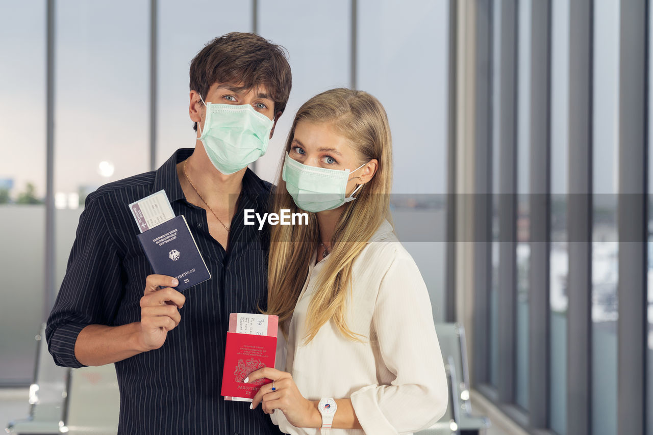 Life during covid-19 pandemic. young man and woman waiting for flying at airport at window