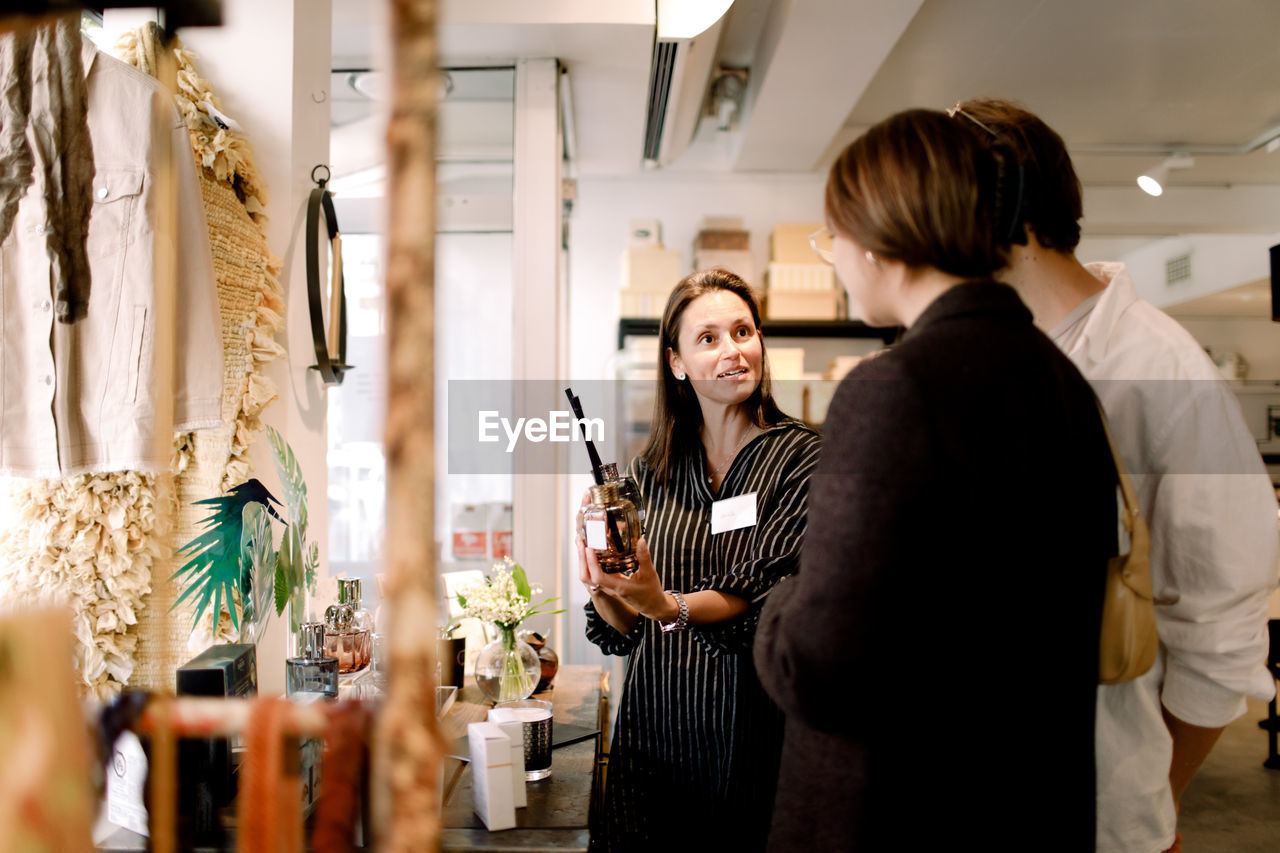 Saleswoman showing perfume to couple at fashion store