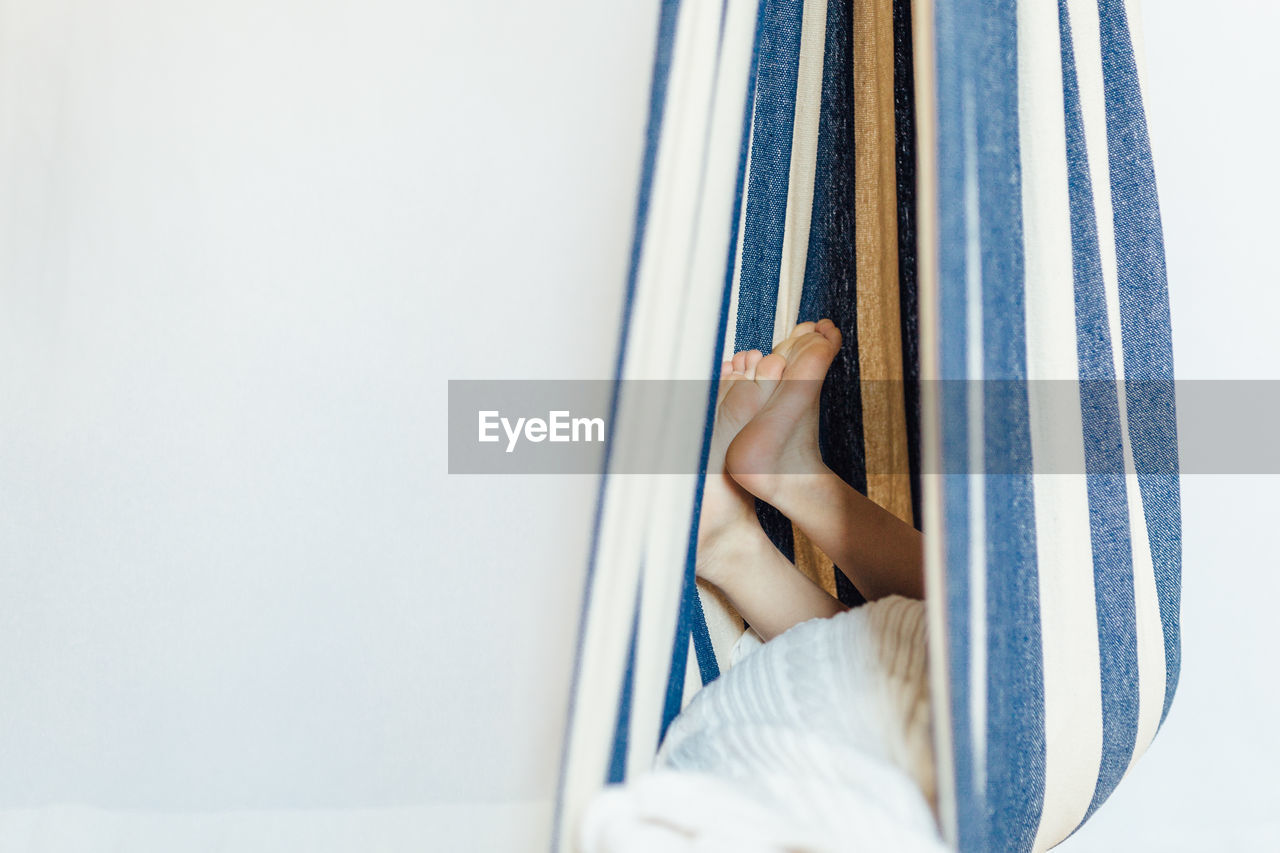 Low section of child relaxing in hammock against white background