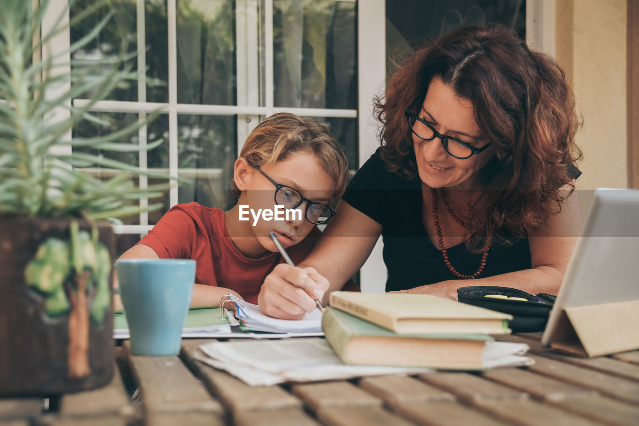 Mature woman helping son with studies at home