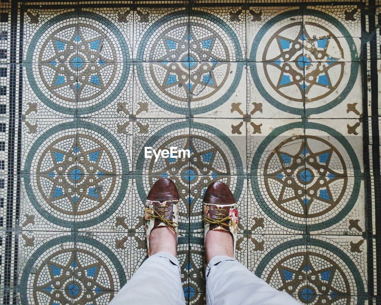 Low section of person standing on pattern tiled floor