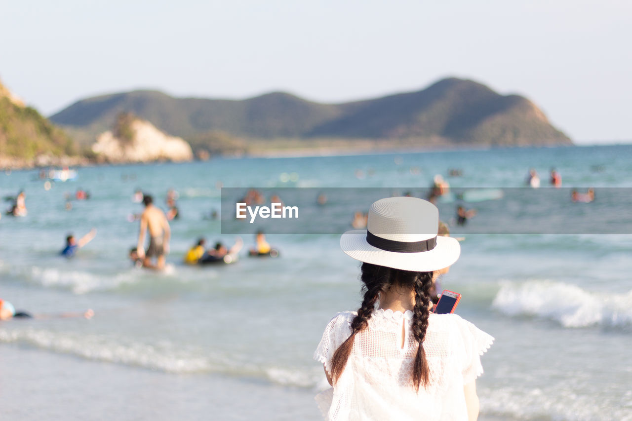 Rear view of woman at beach against sky