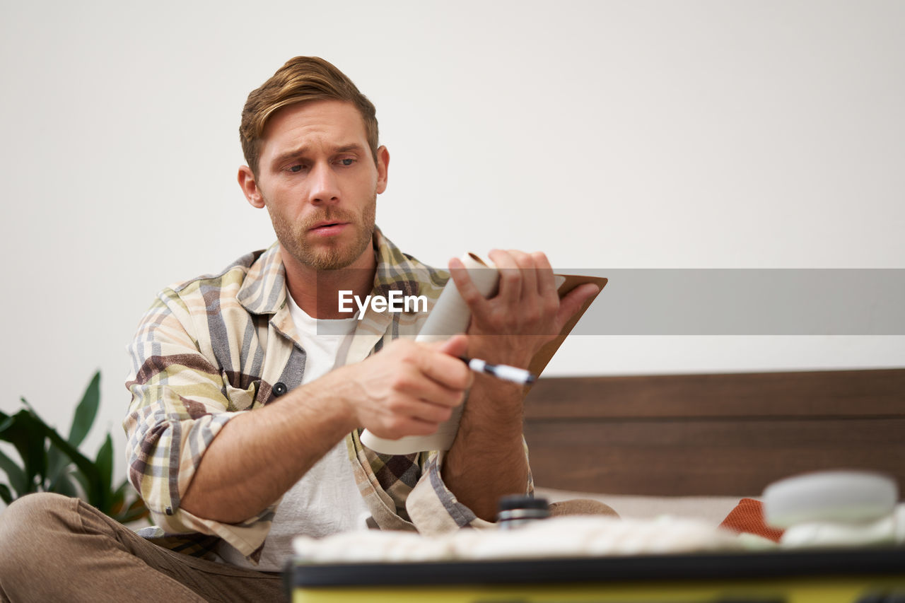 portrait of man using mobile phone while sitting on table