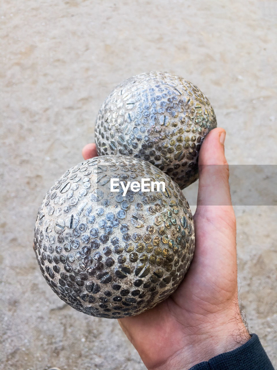 Cropped hand of man holding boccia balls on footpath