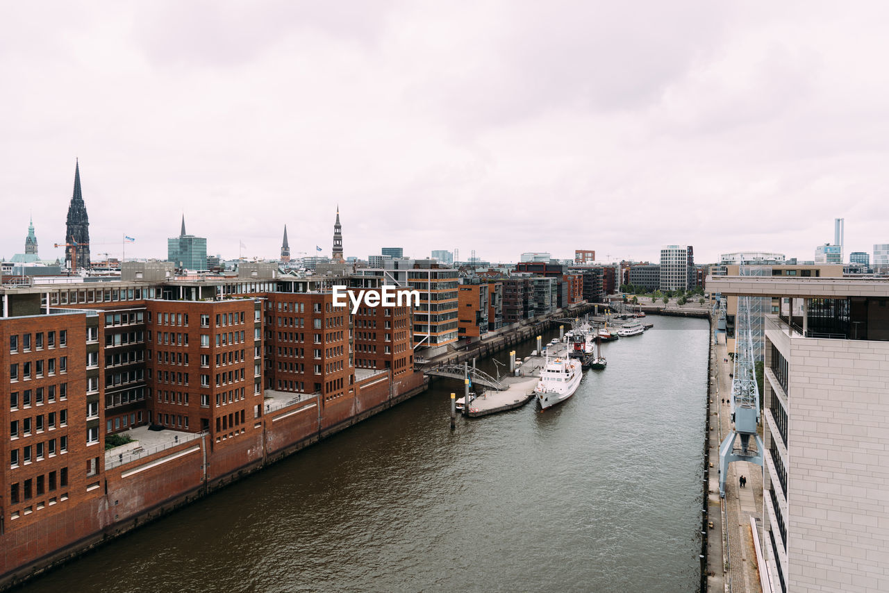 Aerial view of buildings by river against sky