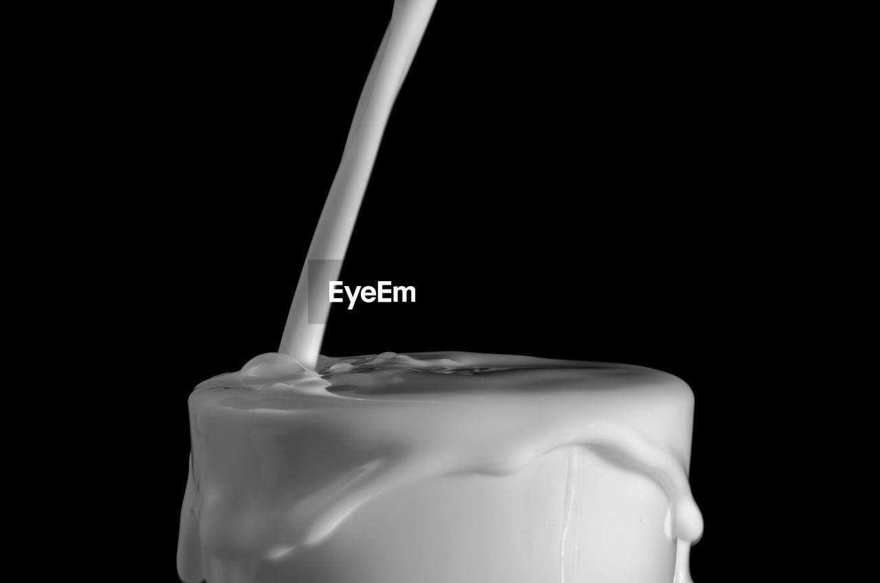 Close-up of pouring milk over black background