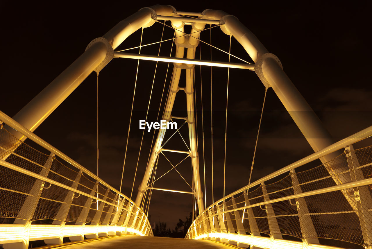 LOW ANGLE VIEW OF BRIDGE IN CITY AT NIGHT
