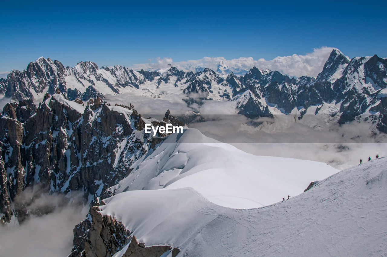 Snowy peaks and mountaineers in a sunny day at the aiguille du midi, near chamonix, france.