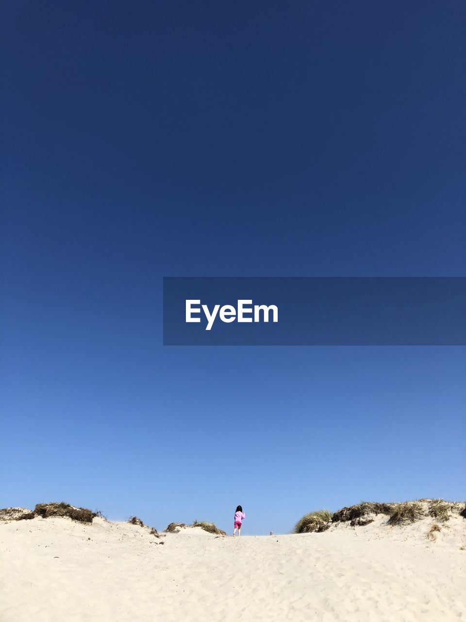 Woman on shore against clear blue sky