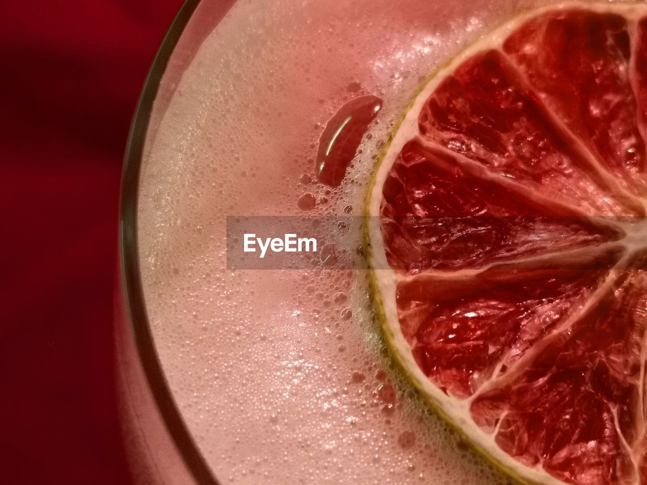 CLOSE-UP OF DRINK IN GLASS AGAINST RED BACKGROUND