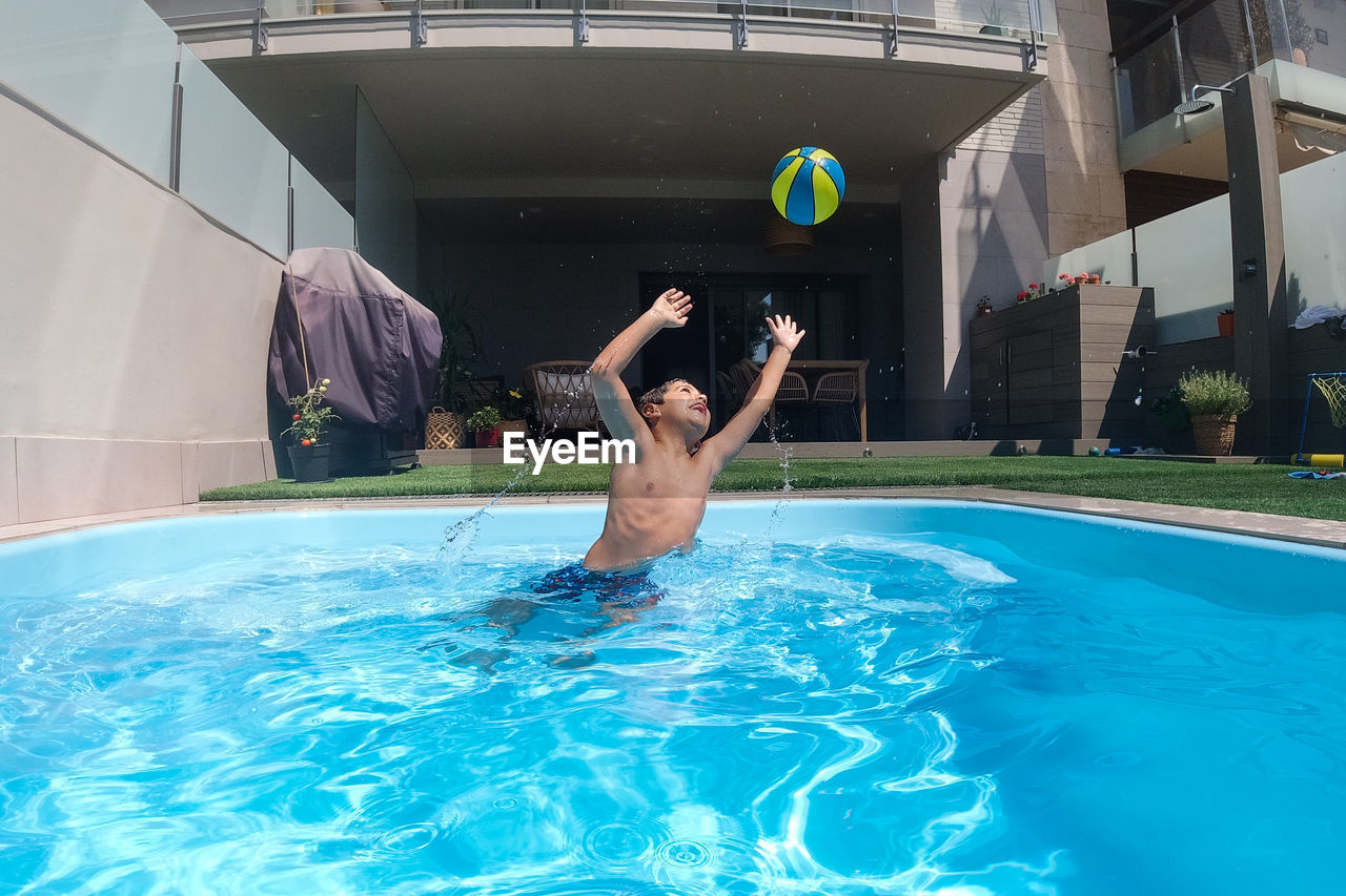 Athletic boy playing with a ball on a swimming pool