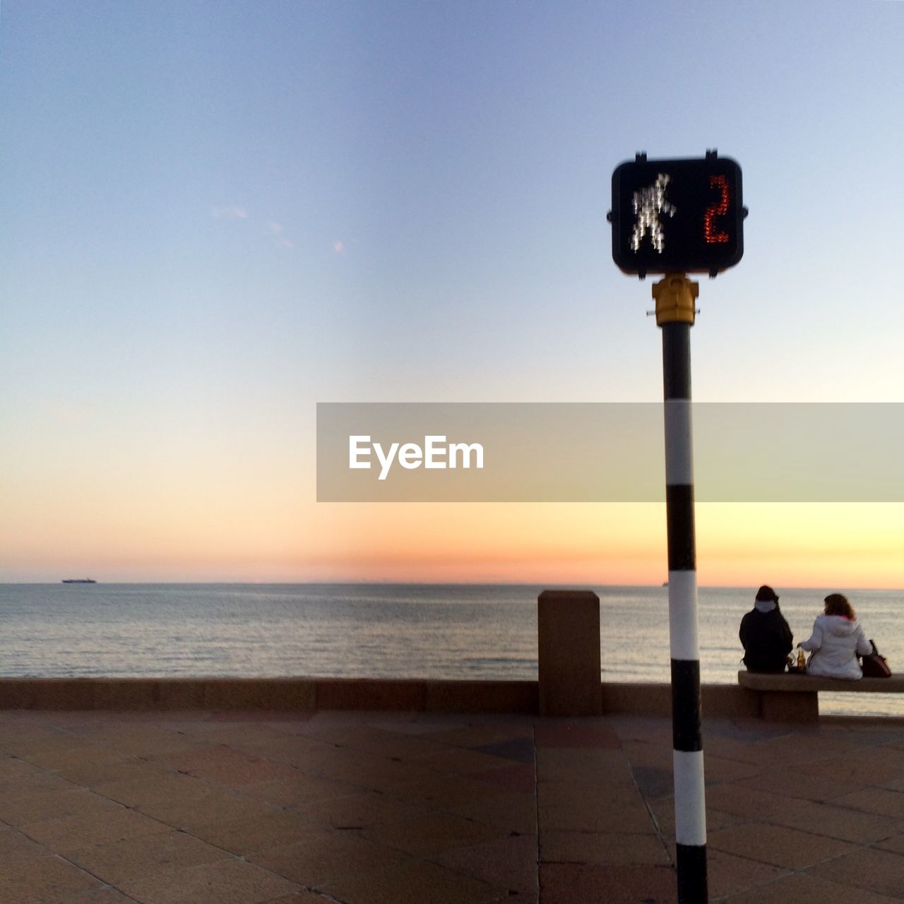 PEOPLE PHOTOGRAPHING SEA AGAINST SKY DURING SUNSET