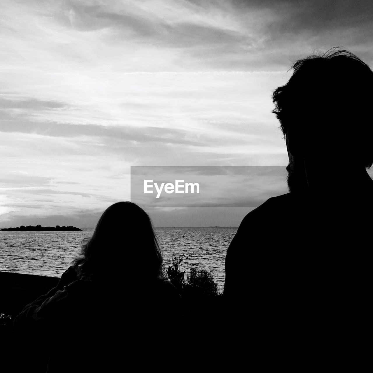 Rear view of young couple overlooking calm sea