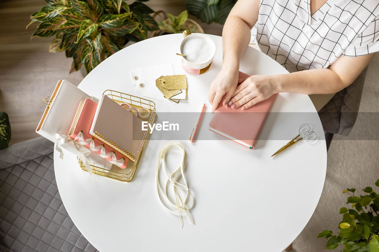 high angle view of woman holding coffee cup on table