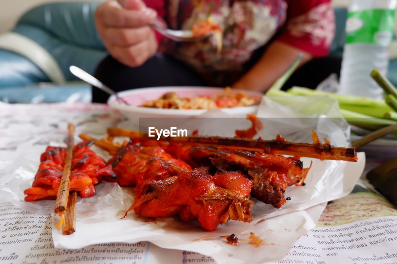 CLOSE-UP OF HAND HOLDING MEAT ON PLATE