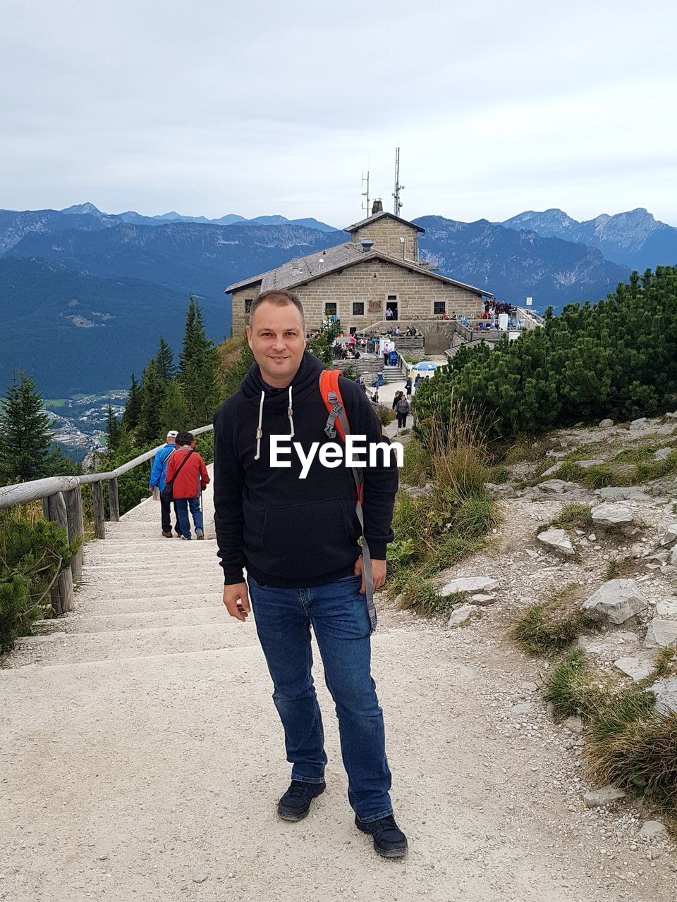 PORTRAIT OF MAN STANDING ON BUILDING AGAINST MOUNTAIN