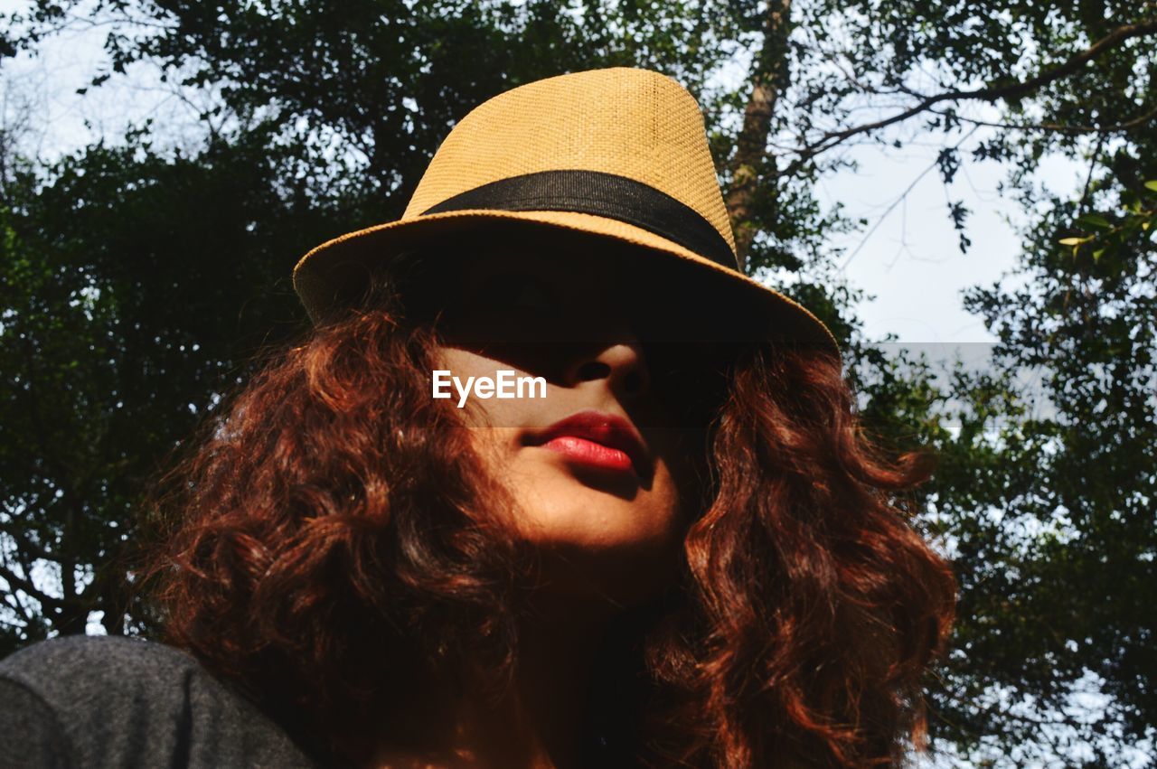 Close-up of young woman wearing hat against trees