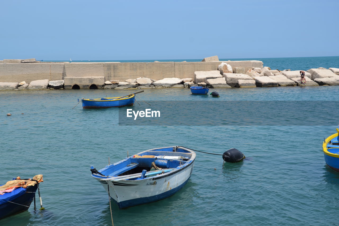 BOATS MOORED IN SEA AGAINST CLEAR SKY