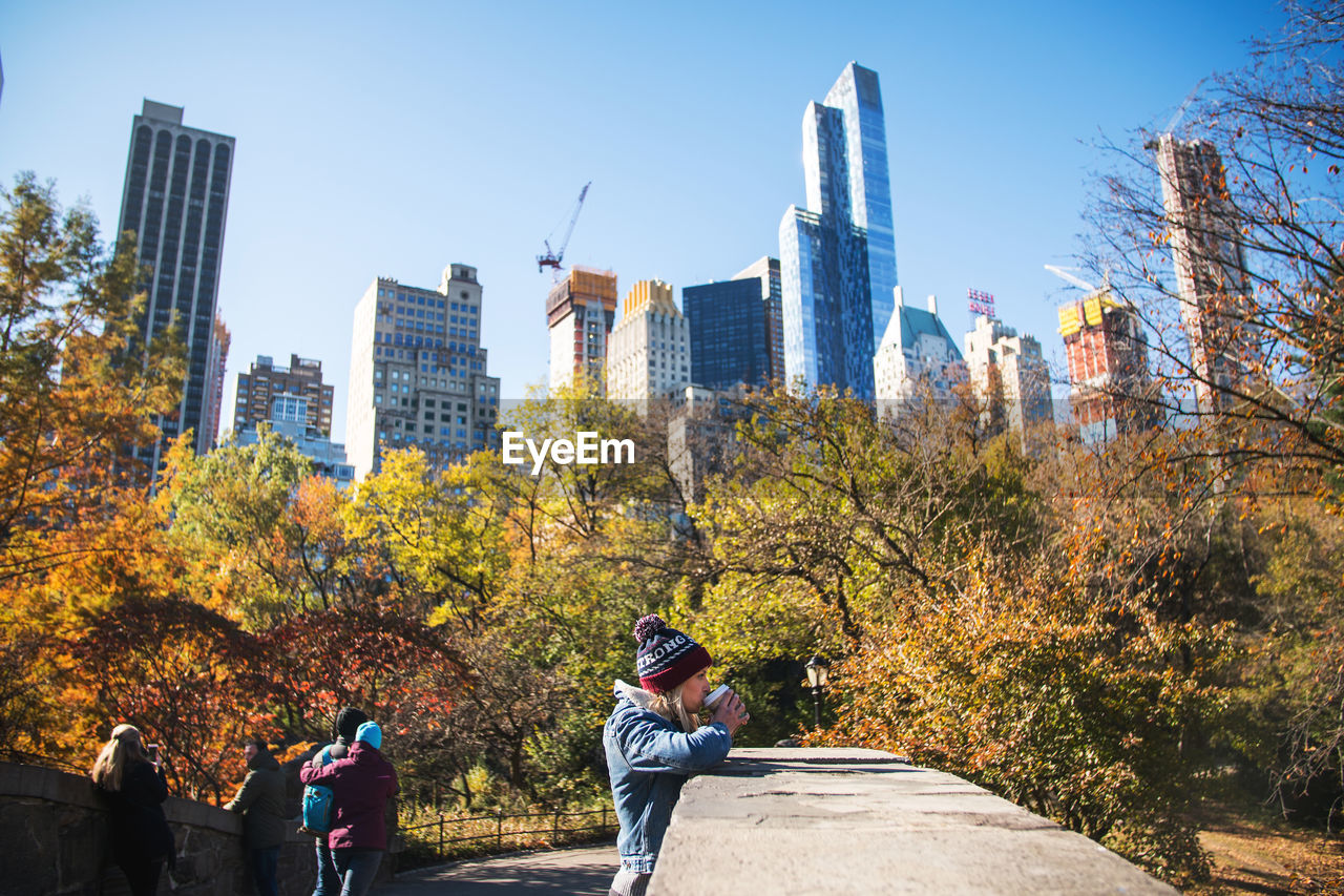 PEOPLE STANDING BY MODERN CITY DURING AUTUMN