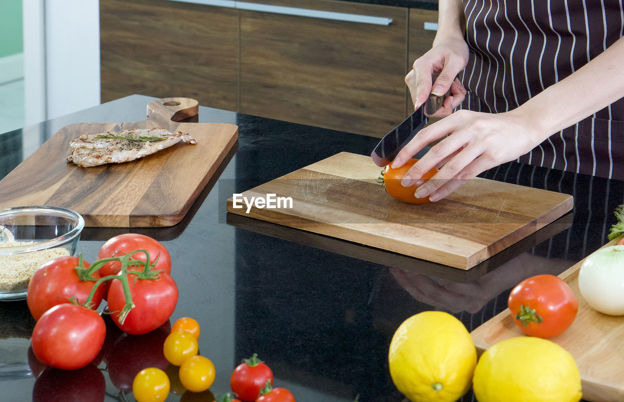 CROPPED IMAGE OF PERSON PREPARING FOOD ON CUTTING BOARD