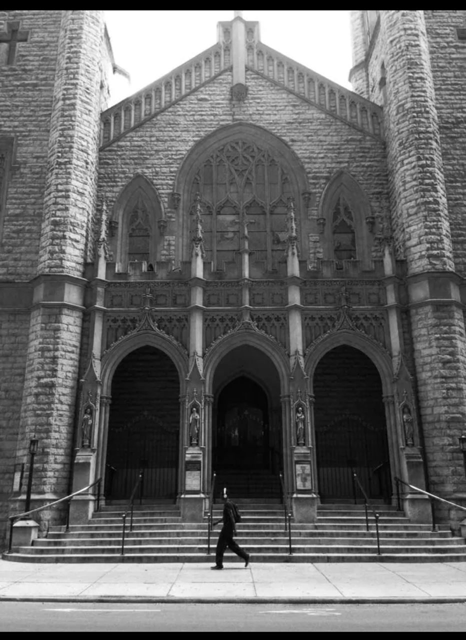 Man walking past gothic church facade