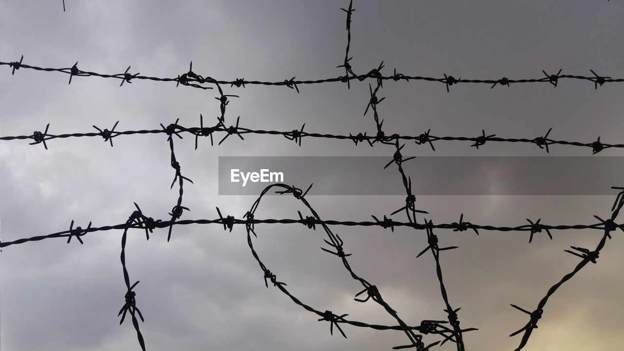 LOW ANGLE VIEW OF BARBED WIRE AGAINST SKY