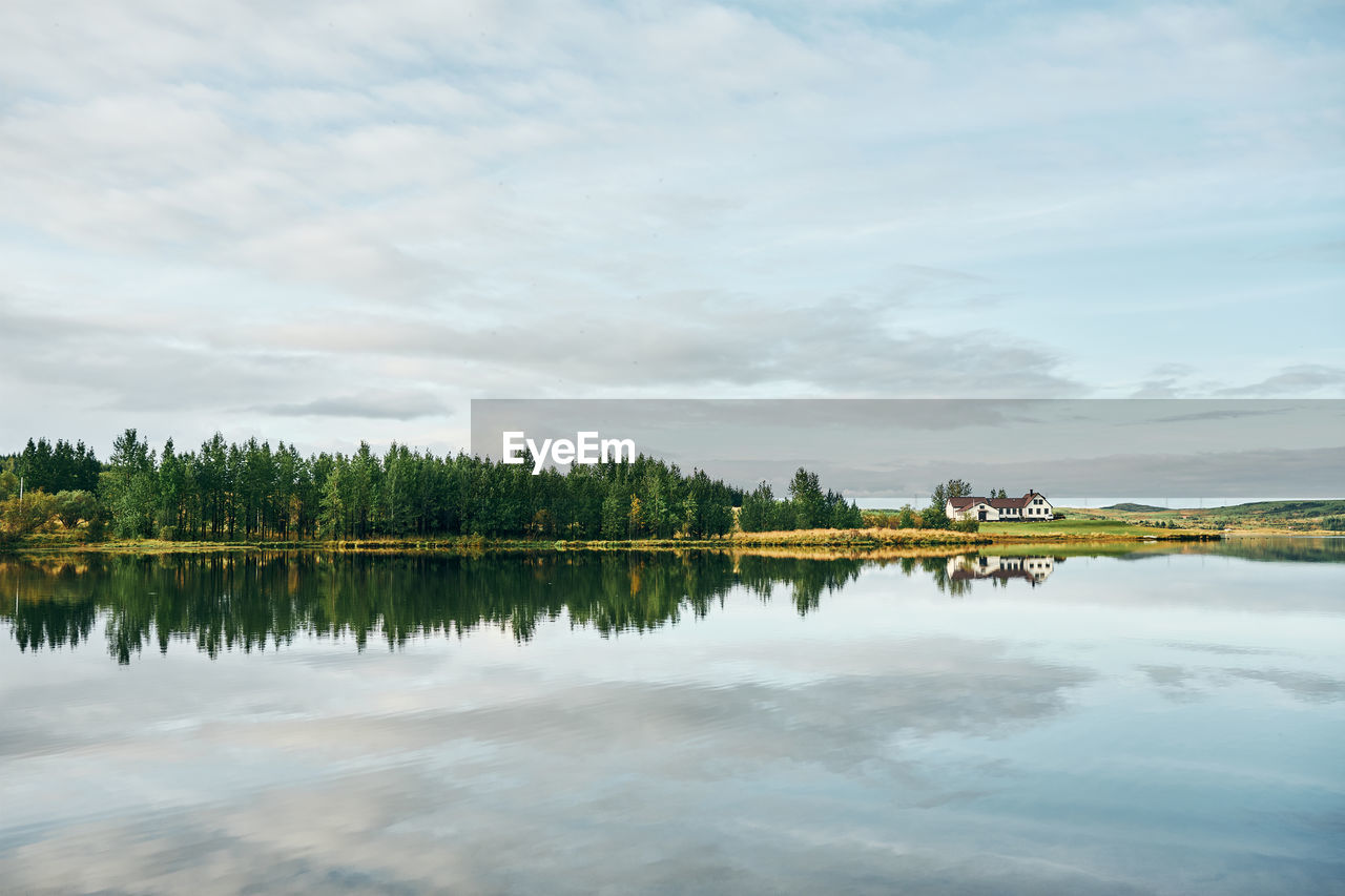 Beautiful landscape of green copse and house on lake shore