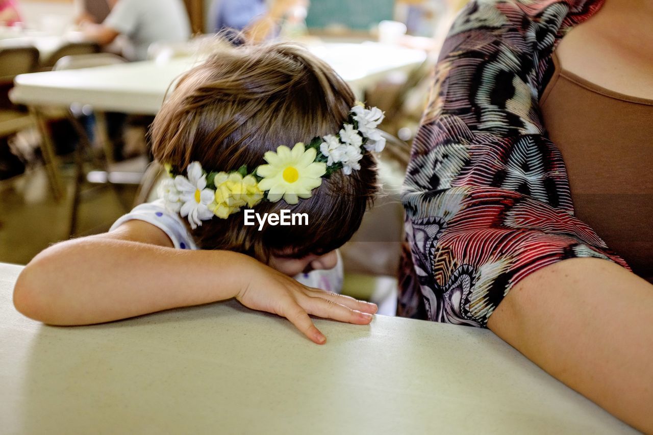 Cropped image of girl sitting by mother at table
