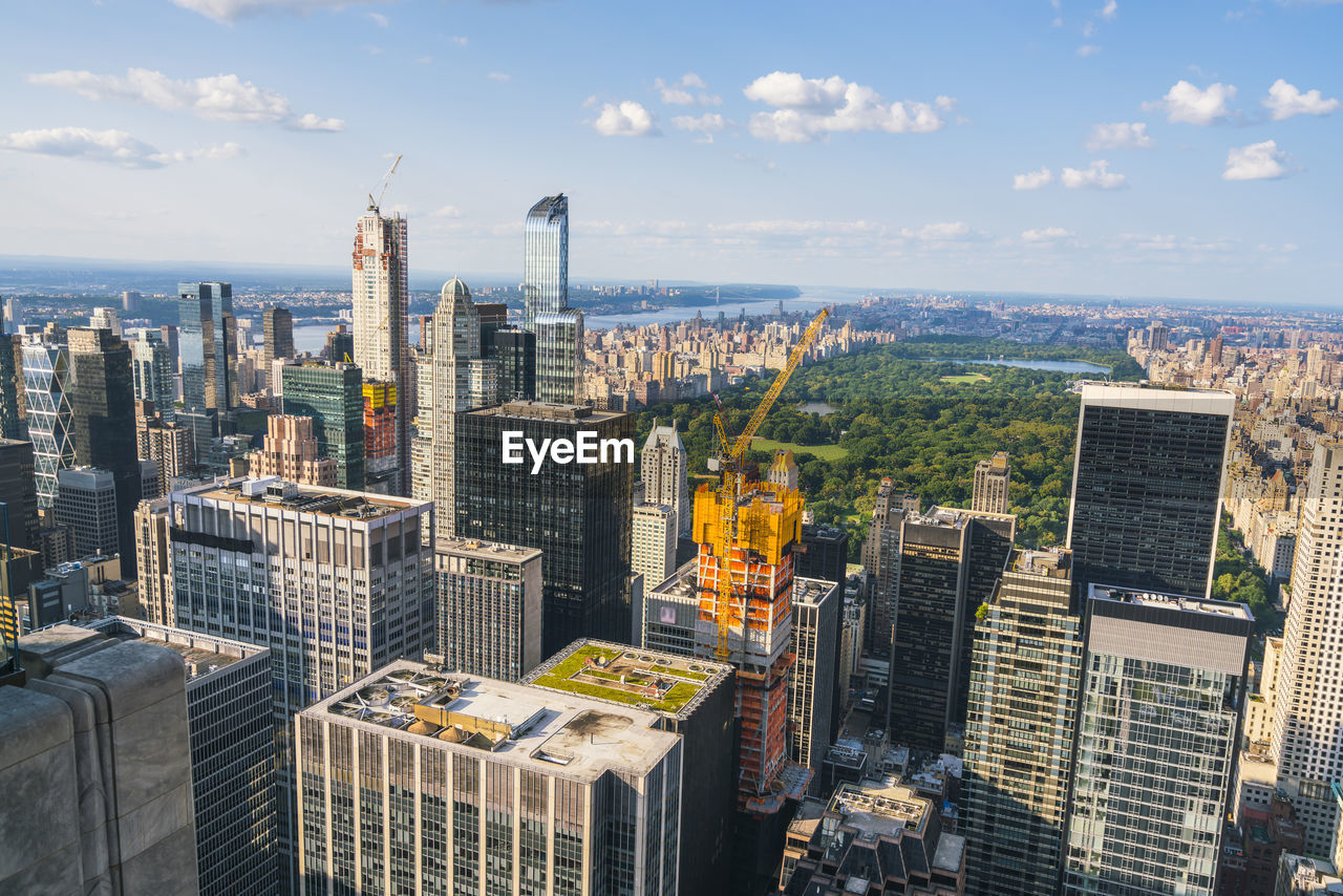 HIGH ANGLE VIEW OF BUILDINGS IN CITY AGAINST CLOUDY SKY