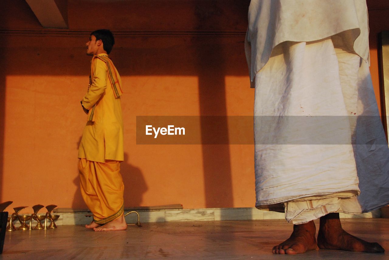 REAR VIEW OF MAN AND WOMAN STANDING ON FLOOR