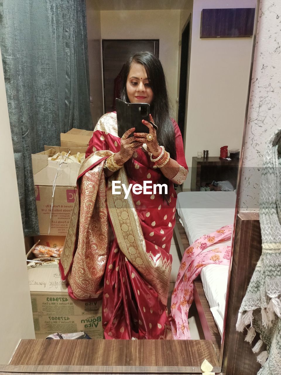 one person, women, clothing, adult, holding, traditional clothing, communication, front view, indoors, female, smiling, wireless technology, dress, portrait, art, architecture, happiness, sitting, lifestyles, emotion, young adult, sari, full length, technology, looking, mobile phone, person, costume, standing, telephone, looking at camera