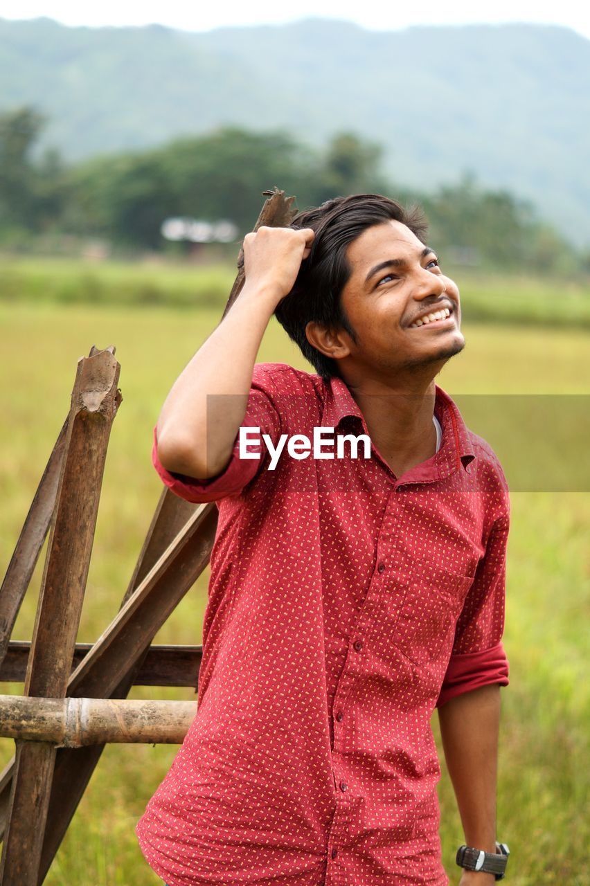 SMILING YOUNG WOMAN LOOKING AWAY ON FIELD
