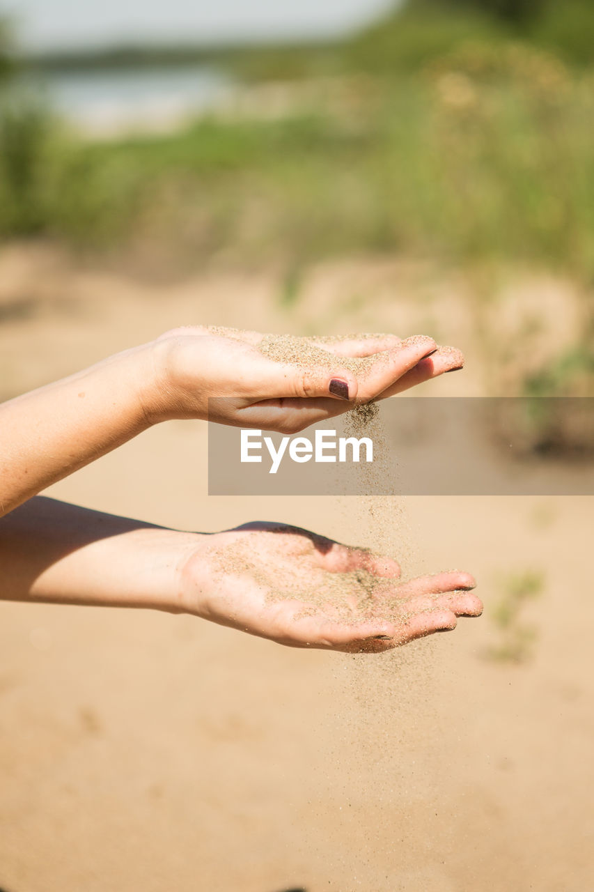 CLOSE-UP OF WOMAN HAND HOLDING SAND